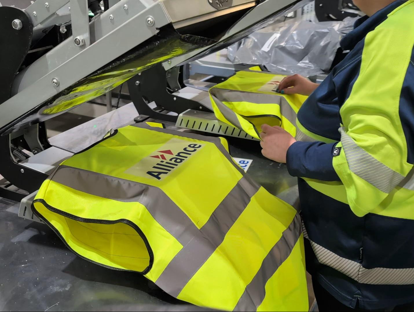 Person in high-visibility safety jacket working with a machine in an industrial setting